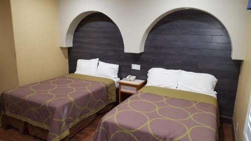 2 camas en una habitación de hotel con 2 arcos en Reedley Inn, en Reedley