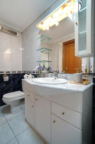 a bathroom with a sink and a toilet and a mirror at GALIHOST - Enorme casa con gran zona exterior en Cambados in Cambados