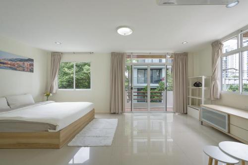 a bedroom with a large white bed and windows at UrbanLoft Sukhumvit 5BR Bangkok 5 min BKK Hospital in Ban Sam Ngam