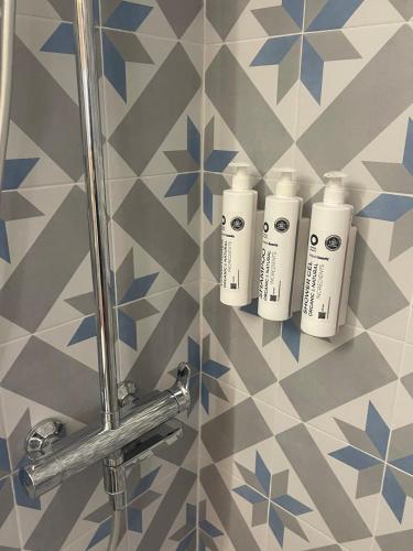 a group of three white bottles on a tile wall at Vaporia Stone House Seaview in Ermoupoli