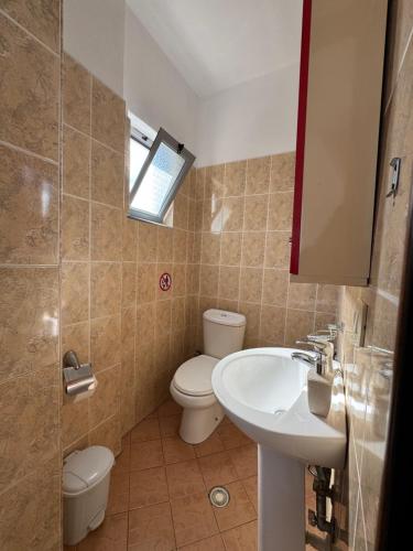 a bathroom with a sink and a toilet and a mirror at Peçi Apartments Gjirokastër in Gjirokastër