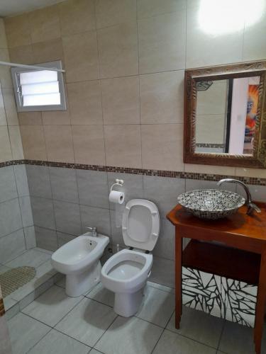 a bathroom with a toilet and a sink and a mirror at El Chañar in Villa Carlos Paz