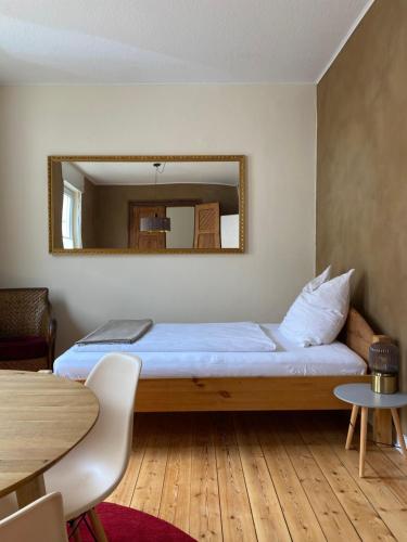 a bedroom with a bed with a mirror and a table at Robins Nest - Charmanter Altbau, 80 m2, zentral & ruhig in Detmold