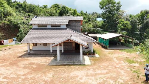 a small house with a building on top of a field at Thotadagadde Homestay in Mudigere