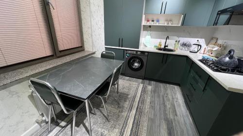cocina con mesa, sillas y lavadora en Квартира APPETIT, en Andiján