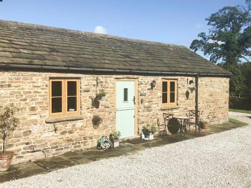 a stone cottage with a white door and windows at The Old Cow Shed in Barlow