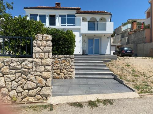 a white house with a stone wall and stairs at Apartment Dubravko mit Meerblick 100 m Strand, Parking in Maslenica
