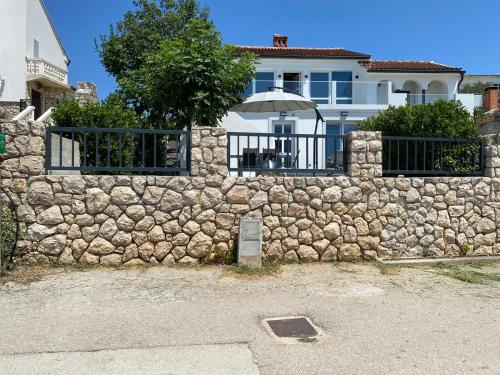 a stone wall with an umbrella in front of a house at Apartment Dubravko mit Meerblick 100 m Strand, Parking in Maslenica