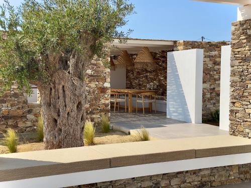 a stone house with a tree in the yard at Farous seaside sunset villa in Agios Georgios