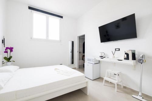 a white room with a bed and a tv on the wall at EnSe Affittacamere in Tortolì