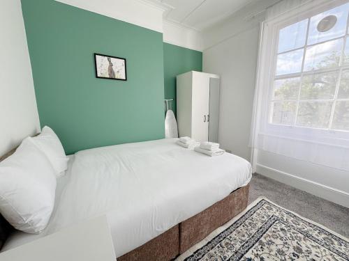 a bedroom with a white bed and a blue wall at Prime Central London 2-Bed by Shops & Transport in London