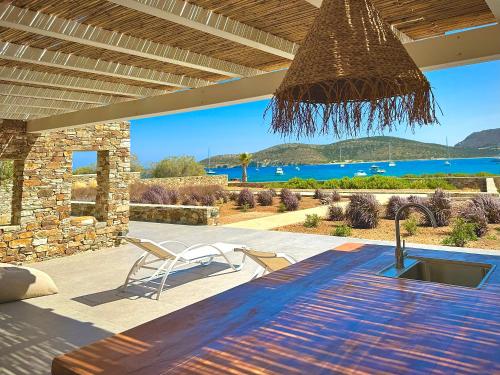 a patio with a wooden table and a view of the water at Farous seaside sunset villa in Agios Georgios