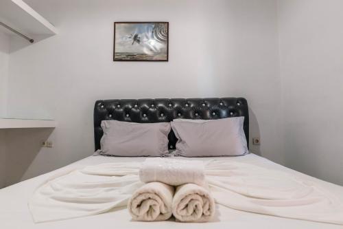 a bed with a black headboard and two towels on it at Andy Apartments in Sarandë