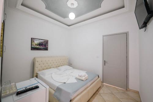 a small white bedroom with a bed and a tv at Andy Apartments in Sarandë