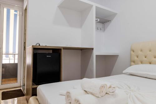 a white bedroom with a bed and a television at Andy Apartments in Sarandë