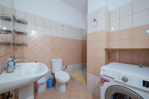 a bathroom with a toilet and a sink and a washing machine at Andy Apartments in Sarandë