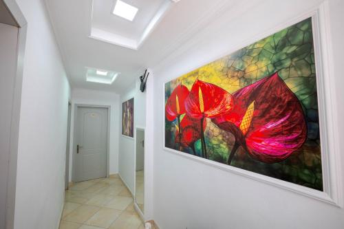 a painting of red flowers hanging on a wall at Andy Apartments in Sarandë
