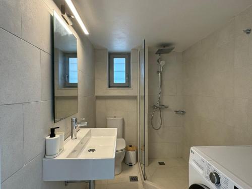 a white bathroom with a sink and a shower at Farous seaside sunset villa in Agios Georgios