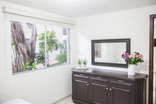 a room with a mirror and a dresser with flowers on it at Suites Lafragua in Veracruz