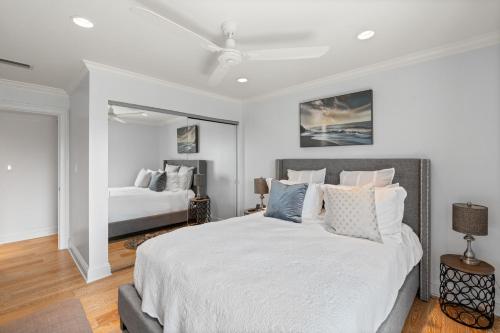 a white bedroom with two beds and a ceiling fan at Just Beachy By Beachside Management in Siesta Key
