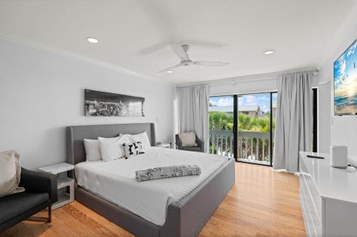 a white bedroom with a bed and a balcony at Just Beachy By Beachside Management in Siesta Key