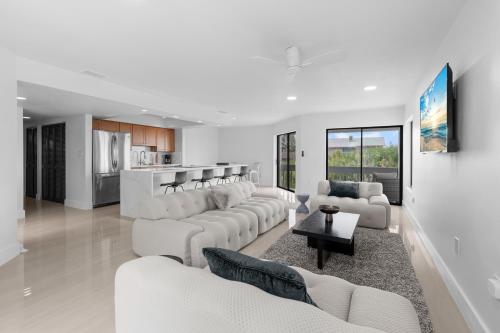a living room with white furniture and a kitchen at Just Beachy By Beachside Management in Siesta Key
