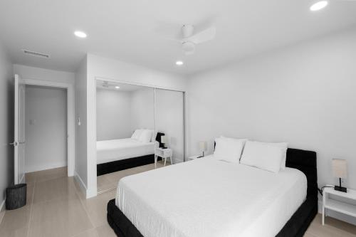 a white bedroom with a large bed and a mirror at Just Beachy By Beachside Management in Siesta Key