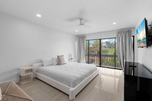 a white bedroom with a bed and a large window at Just Beachy By Beachside Management in Siesta Key