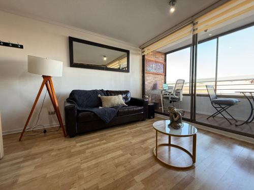 a living room with a black couch and a table at Departamento en Condominio Edificio Innova 306 in Copiapó