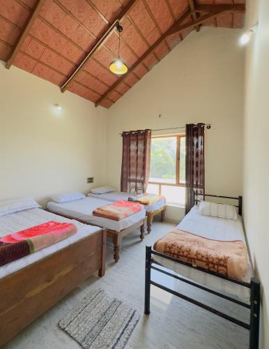 a room with three beds and a window at Thotadagadde Homestay in Mudigere