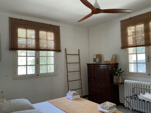 - une chambre avec un ventilateur de plafond et 2 fenêtres dans l'établissement Jolie villa au calme climatisée grande piscine jardin, à Peyriac-de-Mer
