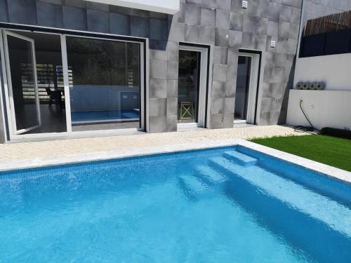 une piscine devant une maison dans l'établissement Casa Alto das Vinhas, à Sesimbra