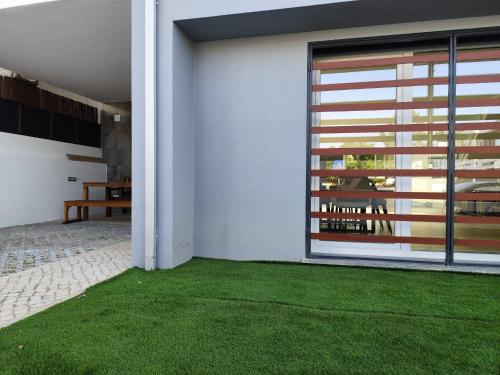 une maison avec une pelouse verte devant une porte dans l'établissement Casa Alto das Vinhas, à Sesimbra