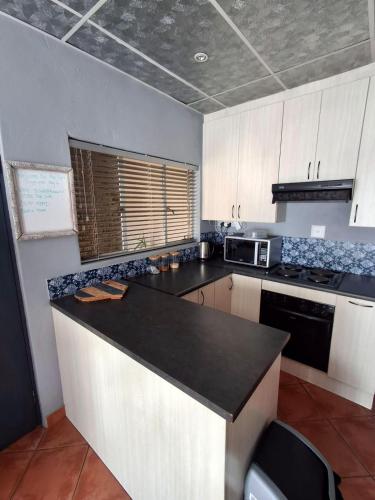 a kitchen with a black counter top and white cabinets at The Loft in Bloemfontein