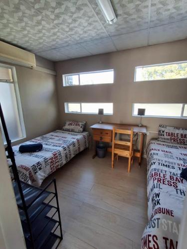 a room with two beds and a desk and a table at The Loft in Bloemfontein