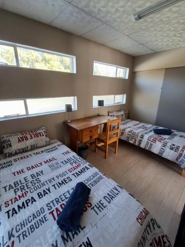 a bedroom with two beds and a desk in it at The Loft in Bloemfontein