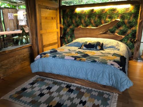 a bed with a comforter with a dog laying on it at "refugio entre montañas" lalomaecolodge in Dosquebradas