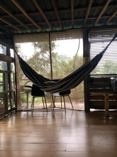 a hammock in a room with two chairs and a window at "refugio entre montañas" lalomaecolodge in Dosquebradas