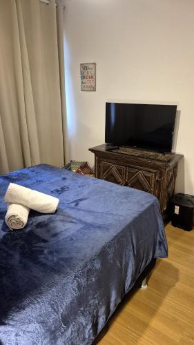 a bedroom with a blue bed and a tv at IPA Guest House - Quarto Aconchegante em Ipanema em apartamento compartilhado - Shared Apartment in Rio de Janeiro