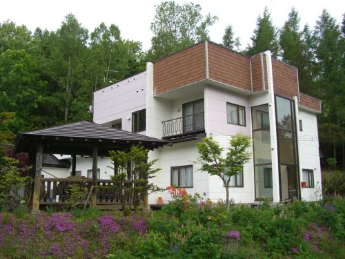a large white house with a brown roof at Coro Coro in Biei