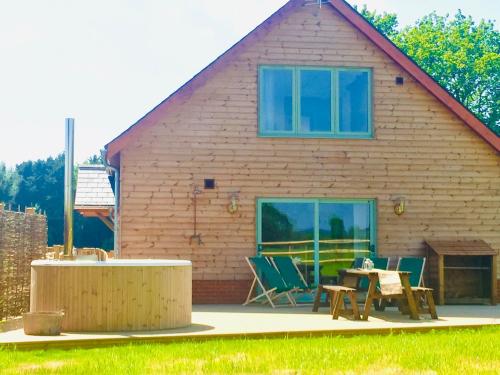 a house with a table and chairs in front of it at Deer Den timber clad cabin with hot tub, up private lane in Cullompton