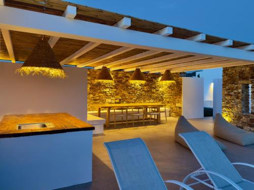 a room with a table and chairs and a stone wall at Farous seaside sunset villa in Agios Georgios