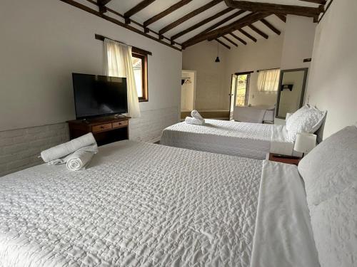 a bedroom with two beds and a flat screen tv at Hotel Montelux in Villa de Leyva