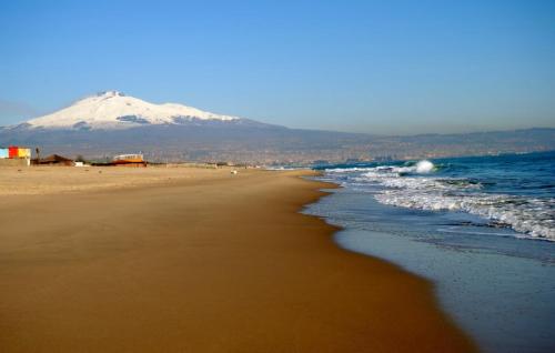 a beach with a snow covered mountain in the background at Asmundo Palace Suites & Spa in Catania