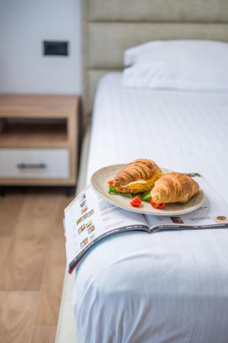 a plate of food on a book on a bed at Hotel Juza in Borsh