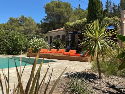une cour arrière avec une piscine et des chaises orange et une maison dans l'établissement Jolie villa au calme climatisée grande piscine jardin, à Peyriac-de-Mer