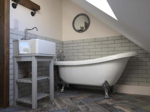 a bathroom with a white tub and a sink at Deer Den timber clad cabin with hot tub, up private lane in Cullompton