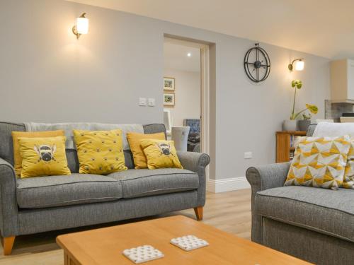a living room with a gray couch and yellow pillows at Bumble Cottage in Cockermouth