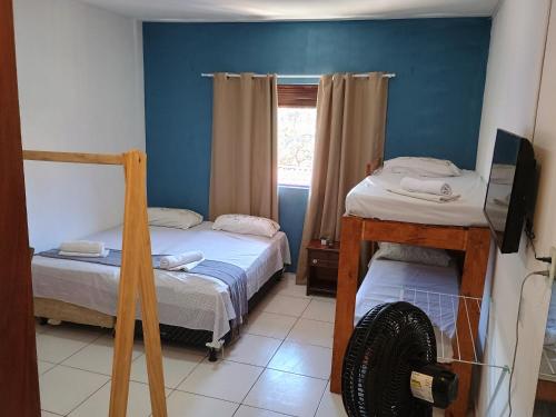 a small room with two beds and a television at Flats Mundos Pipa in Pipa