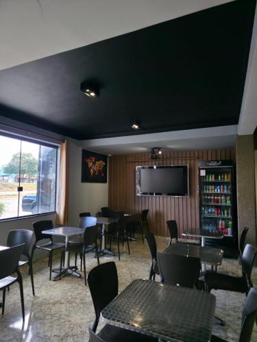 ein Restaurant mit Tischen und Stühlen und einem Flachbildfernseher in der Unterkunft Hotel Uirapuru in Alexânia